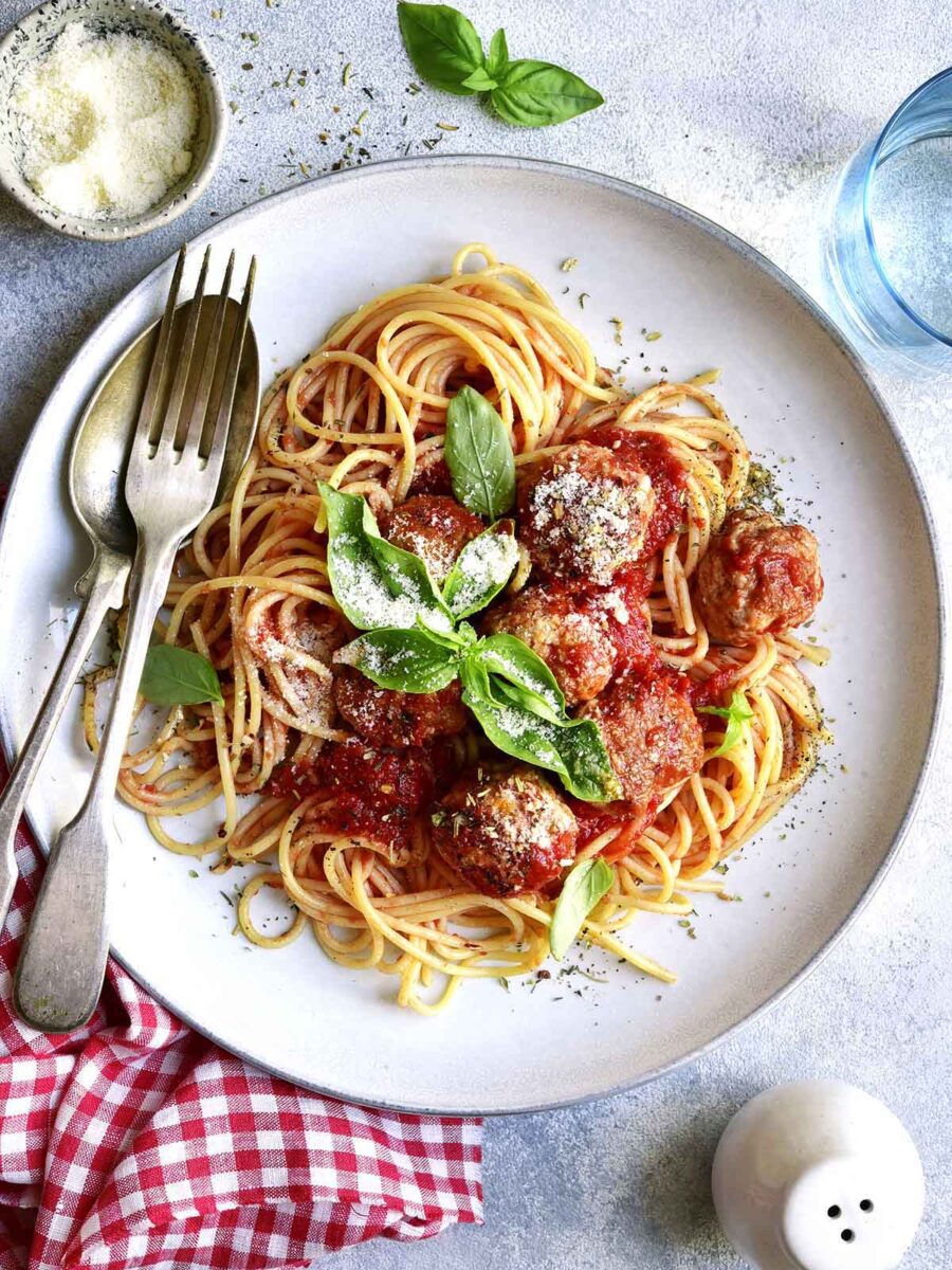 A plate with spaghetti topped with sauce and meatballs.