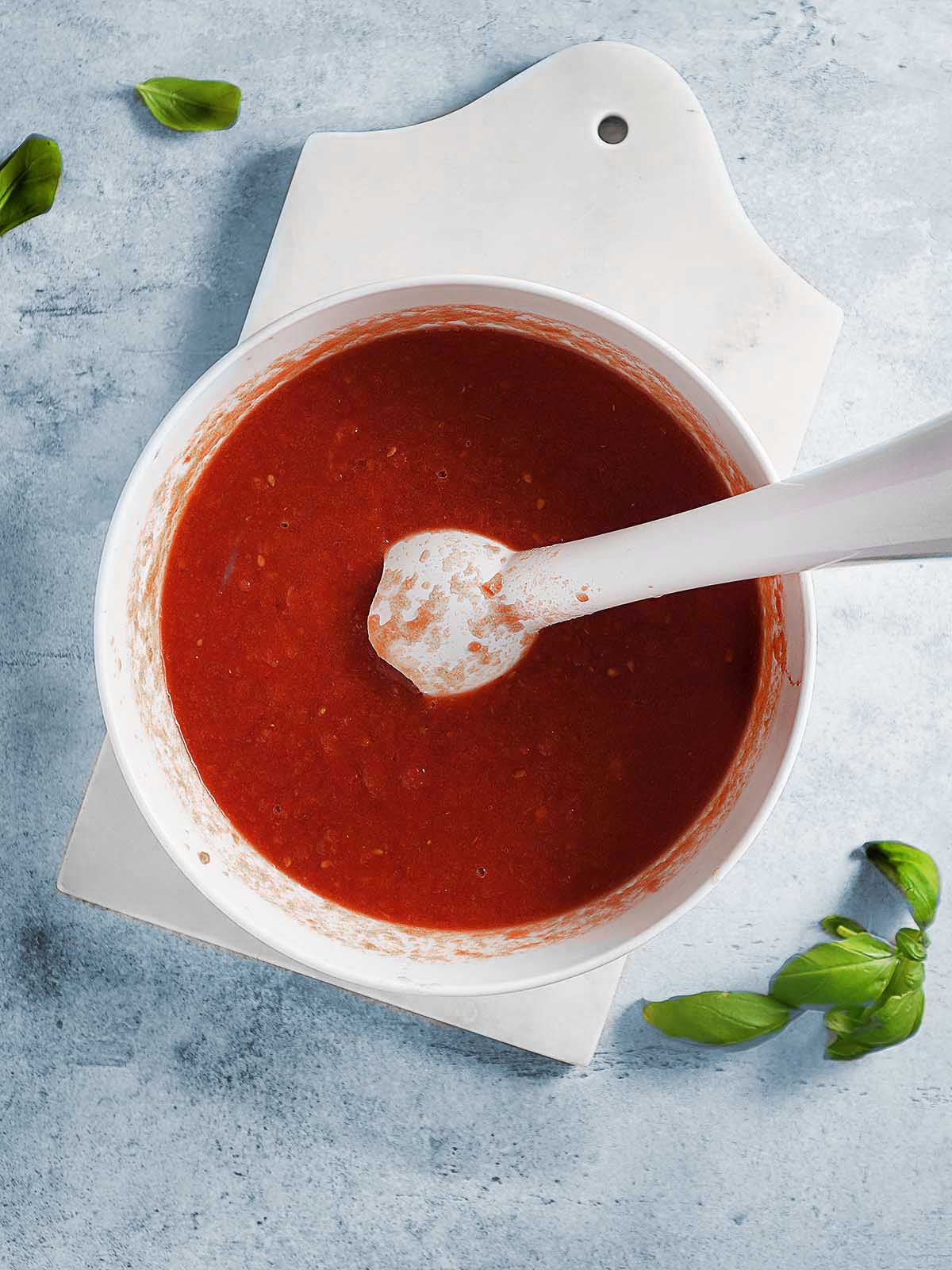 Pureeing canned tomatoes with a immersion blender.