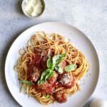 A plate with spaghetti topped with sauce and meatballs.