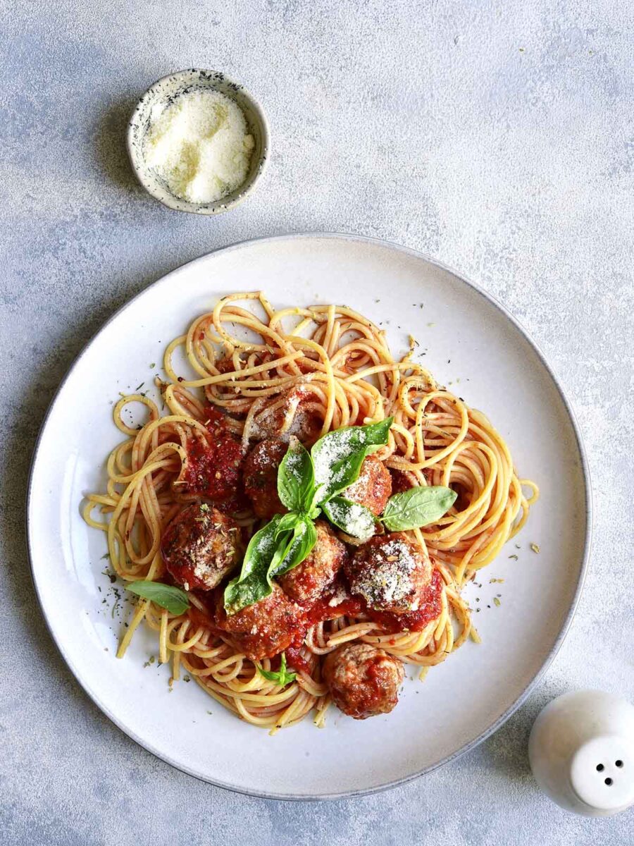 A plate with spaghetti topped with sauce and meatballs.