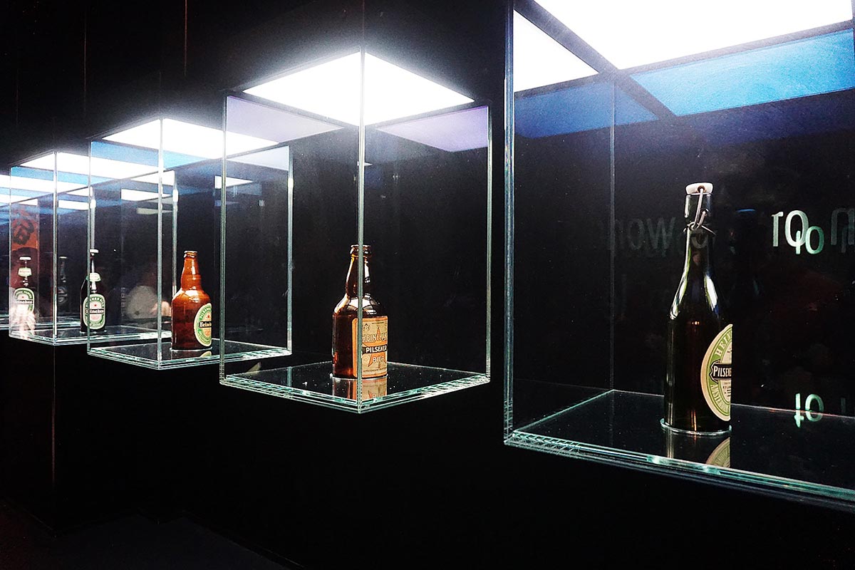 Three beer bottles in a glass case.