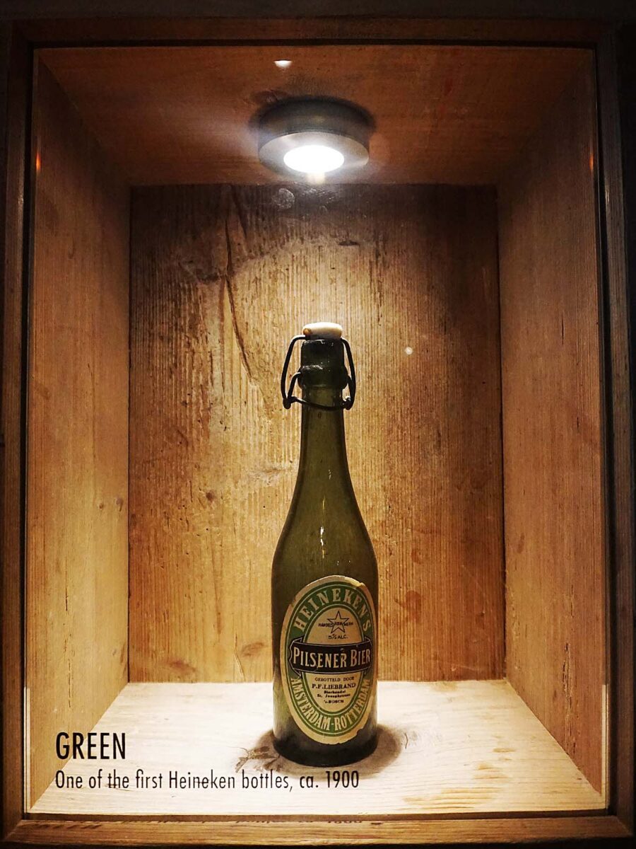 A vintage beer bottle in a glass cage.