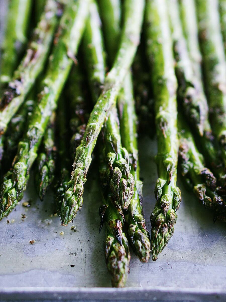 A close up image of roasted asparagus on the baking tray.