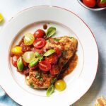 Chicken with vegetables on top of a white plate.