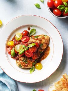 Chicken with vegetables on top of a white plate.