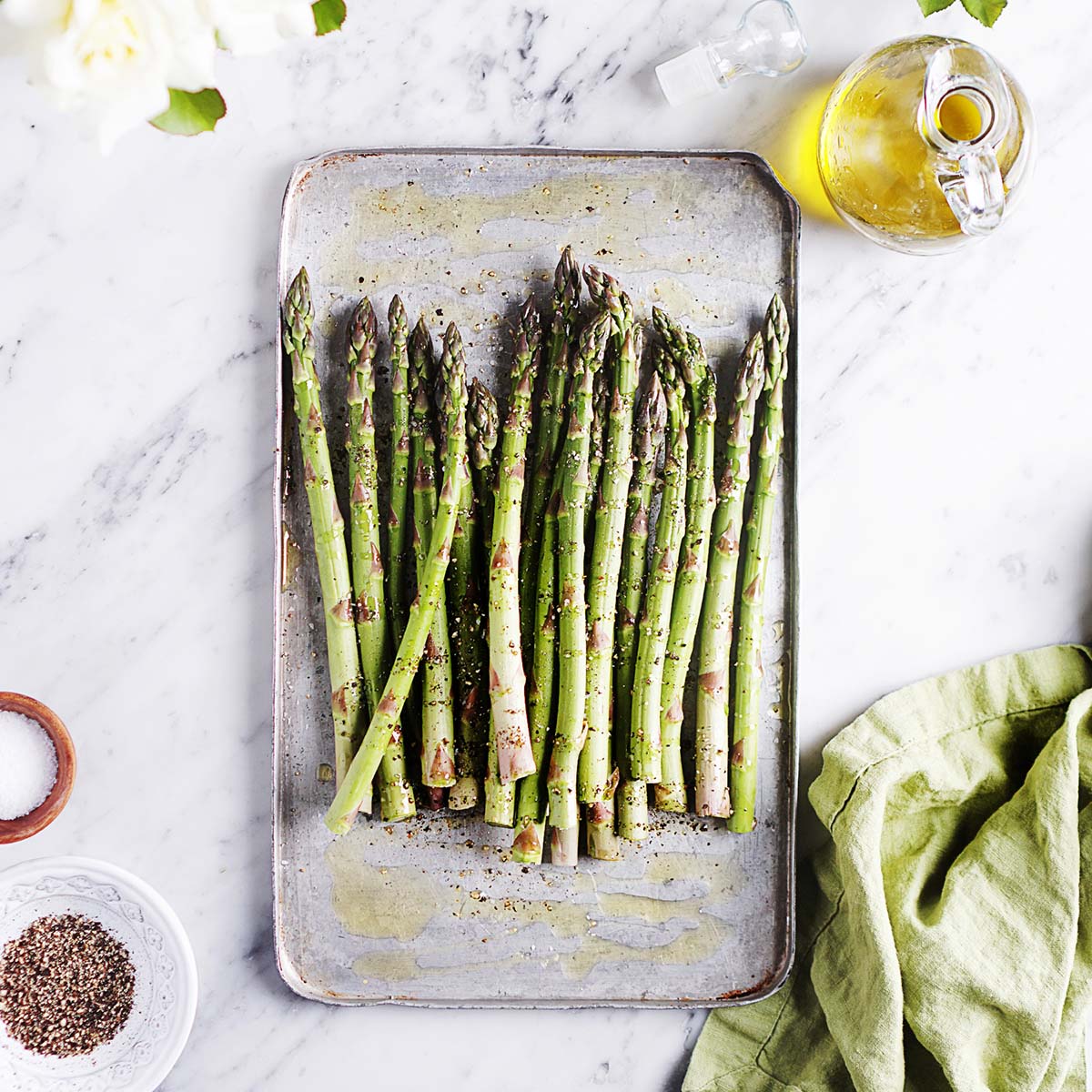 Asparagus placed on a baking tray seasoned with salt and pepper.