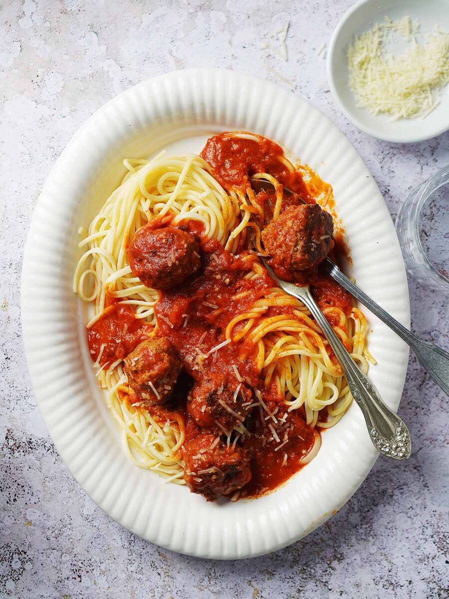 An bowl with meatballs over spaghetti and sauce.