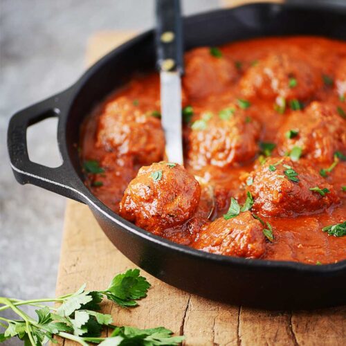 Beef meatballs in a skillet with marinara sauce.