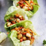 Three shrimp lettuce wraps placed on a metal tray.