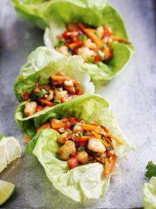 Three shrimp lettuce wraps placed on a metal tray.
