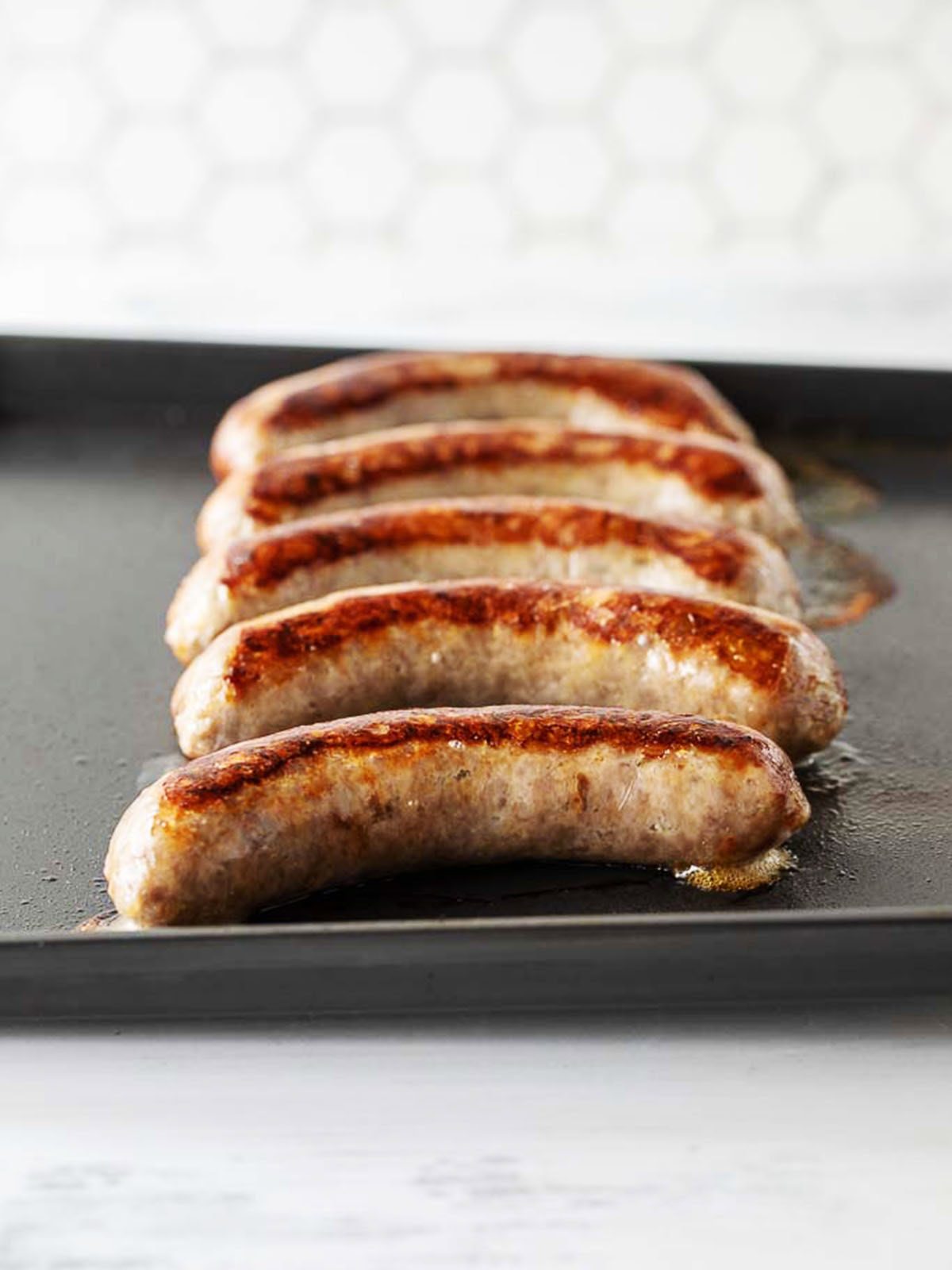 Johnsonville brats on an air fryer tray after cooking.