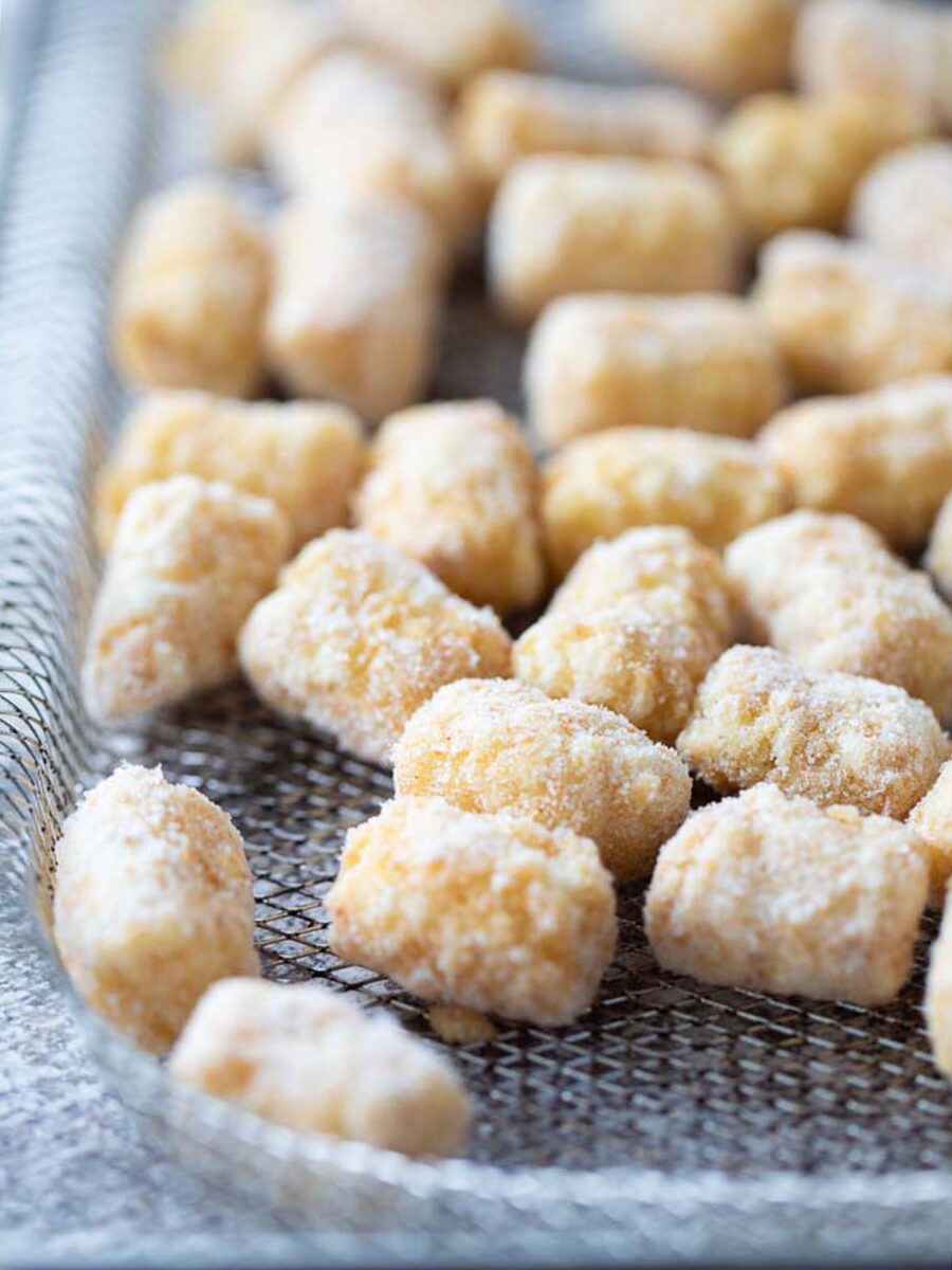 A pile of frozen tater tots on a wire cooling rack.