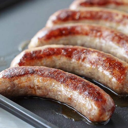 Johnsonville brats on an air fryer tray after cooking.
