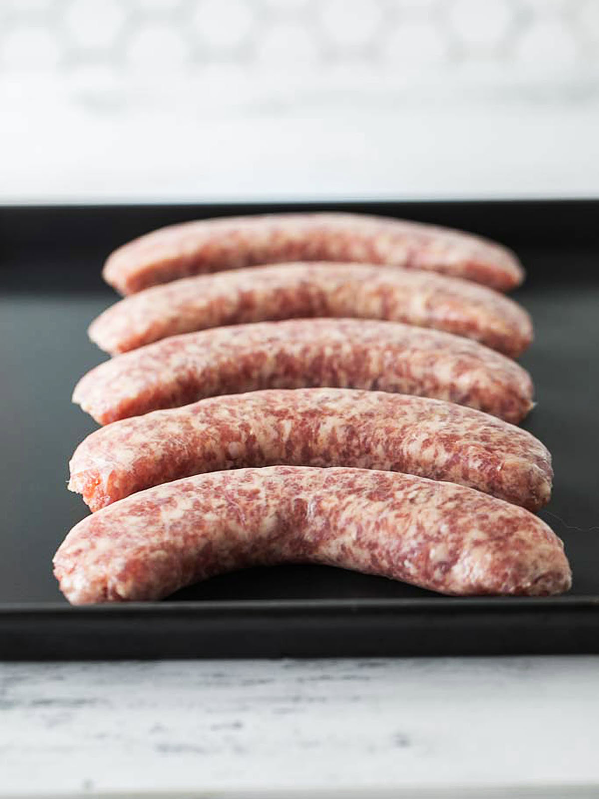 Johnsonville brats on an air fryer tray before cooking.