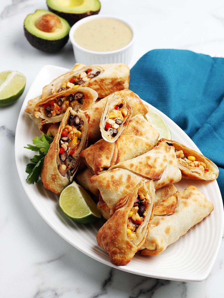 Cooked southwest eggs rolls, some cut in half, on a serving platter.