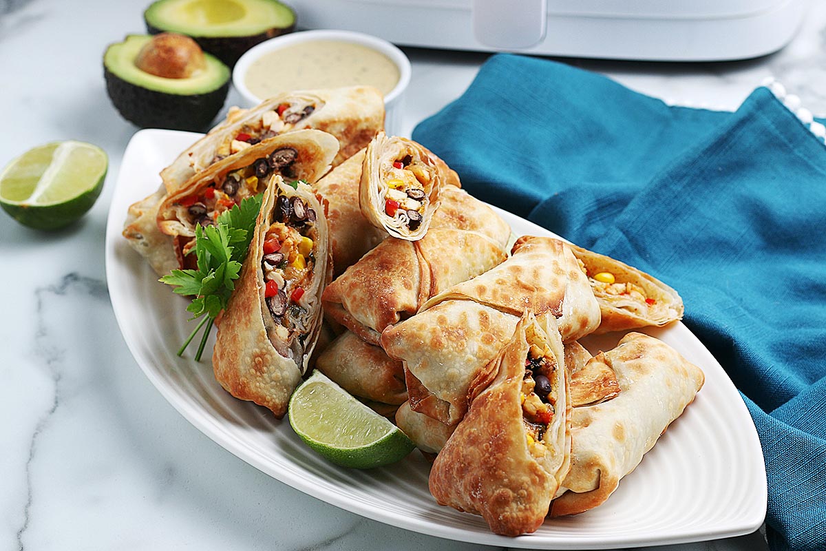 Cooked southwest eggs rolls, some cut in half, on a serving platter.