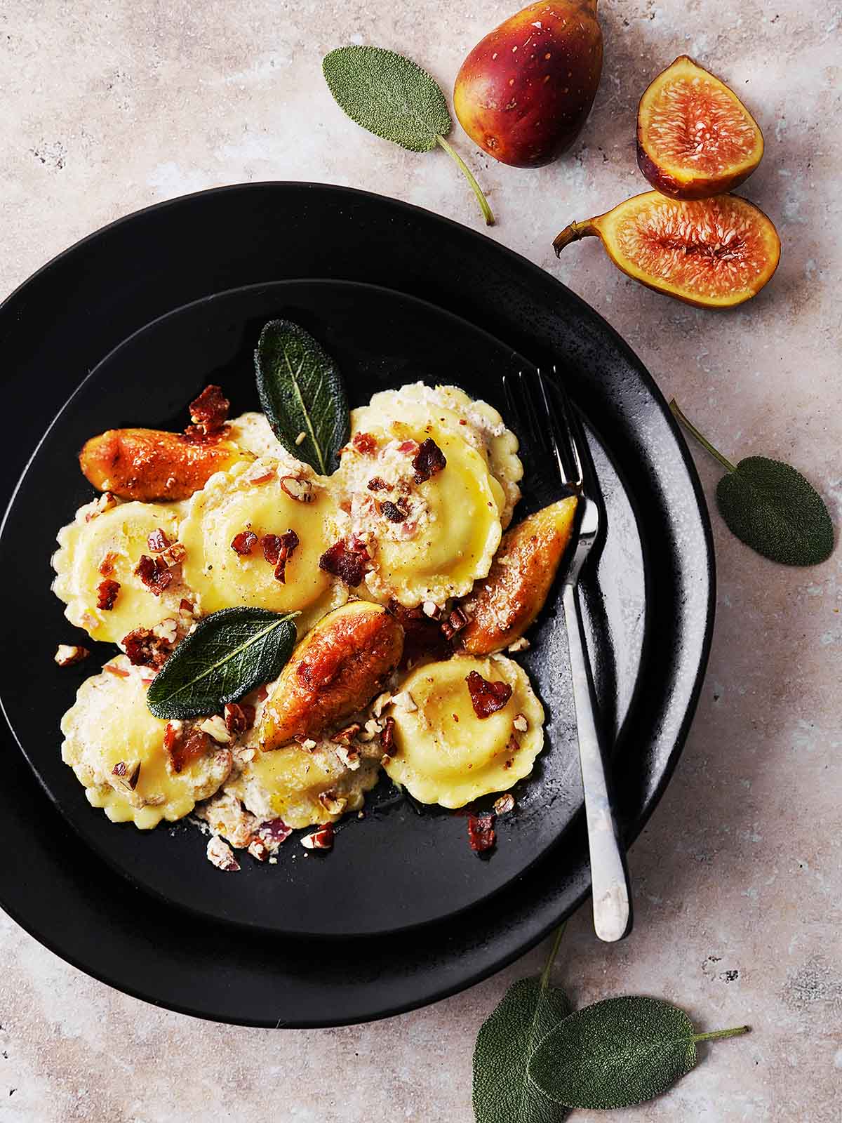 A black plate with cooked Ravioli with Figs, Bacon & Sage.